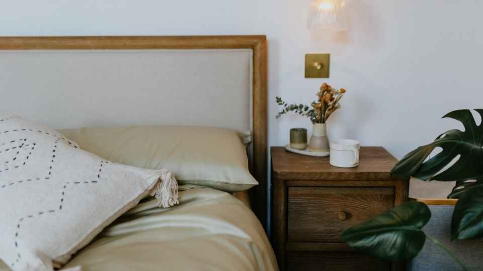A view of a well made bed with beautiful bedding and a small wooden nedside table