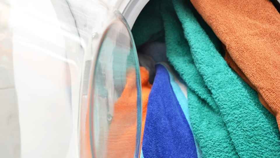 Colourful clothes are being pulled out of a white washing machine