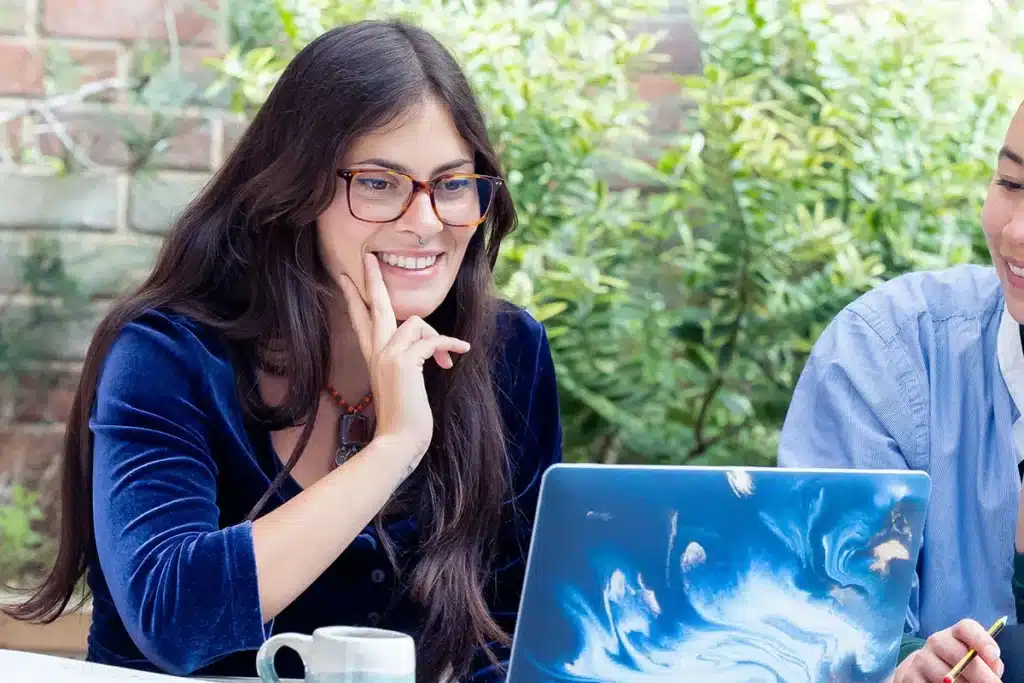 Women smiling looking at laptop screen.