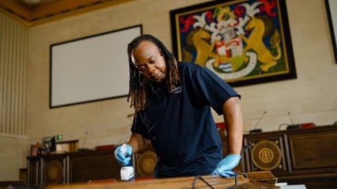 Black woman from Bristol Waste cleaning an office