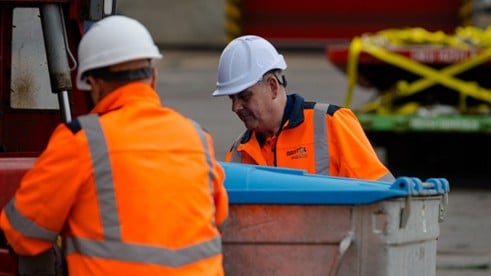 two men in high vis emptying a bin