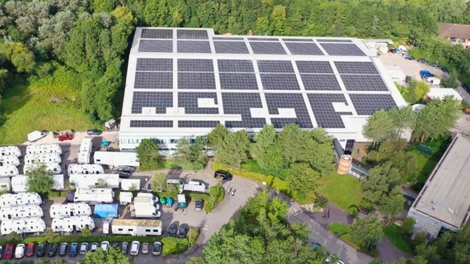 Aerial view of a warehouse with solar panels on the roof.