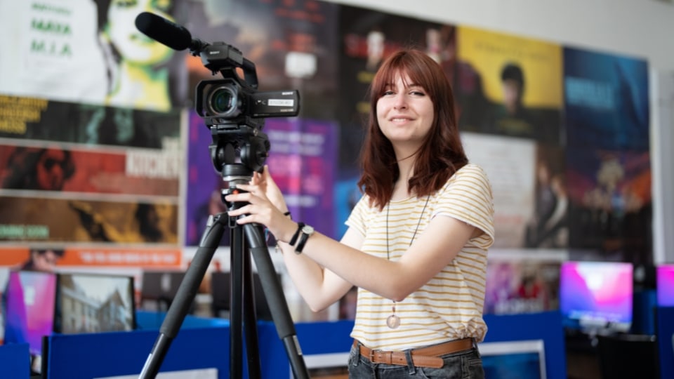 Person operating a camera on a tripod in a clasrrom.